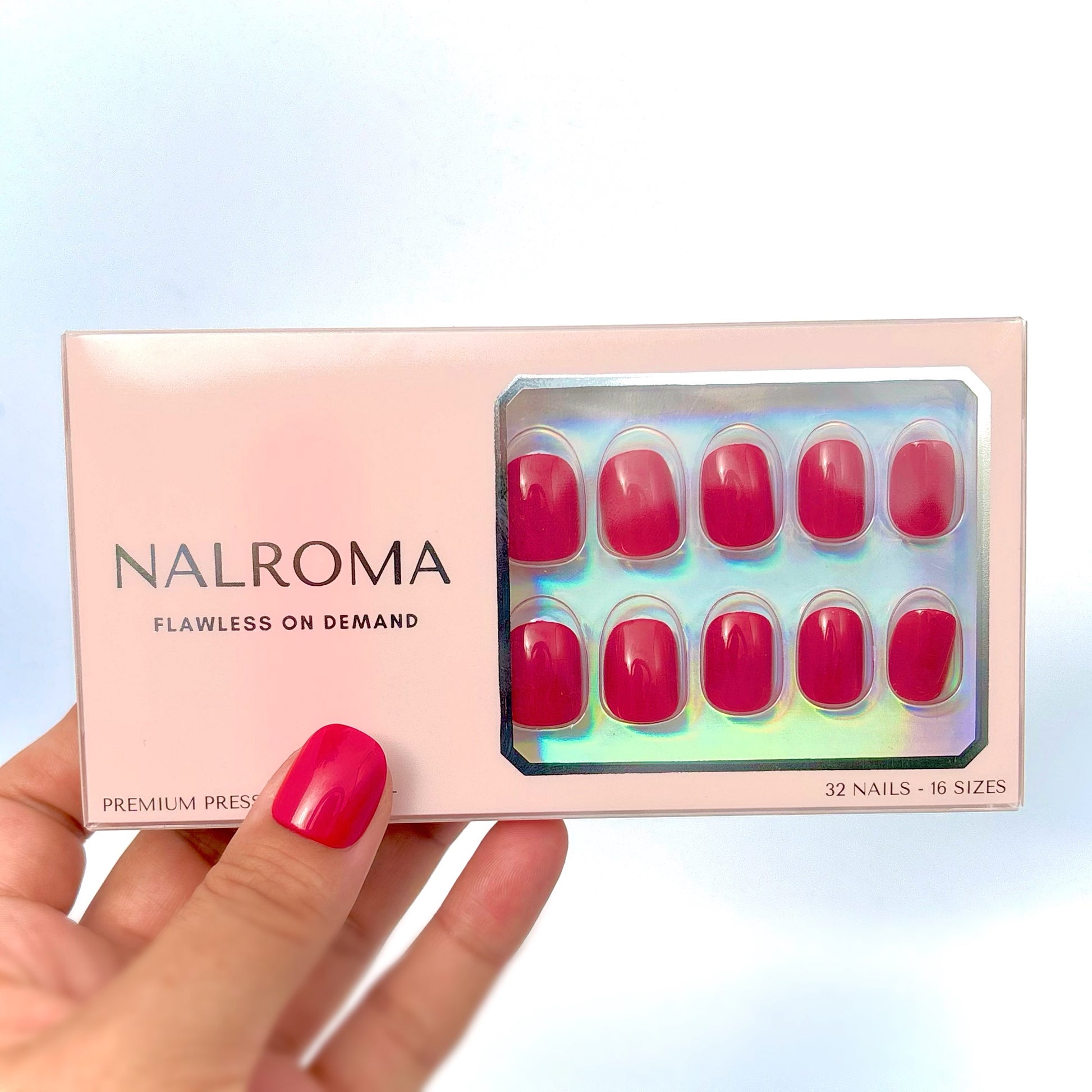 Cherry Rouge Petite extra short round press-on nails in deep cherry red. Red, shiny and glossy, displayed in the beautiful pink packaging with the words printed in a shiny reflective silver.  Contains the words, NALROMA, FLAWLESS ON DEMAND, PREMIUM PREEON NAILS. 32 Nails, 16 sizes. 